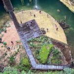 Vue plongeante sur un cénote ouvert, avec ses passerelles en bois et ses baigneurs, près de Cancún