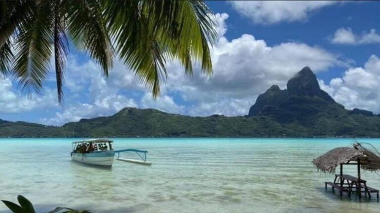 Le lagon turquoise de Bora Bora et le mont Otemanu vus depuis la plage, sous les palmiers