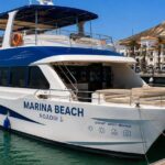 Un bateau d'excursion amarre dans le port d'Agadir, avec la colline et son inscription en arriere-plan