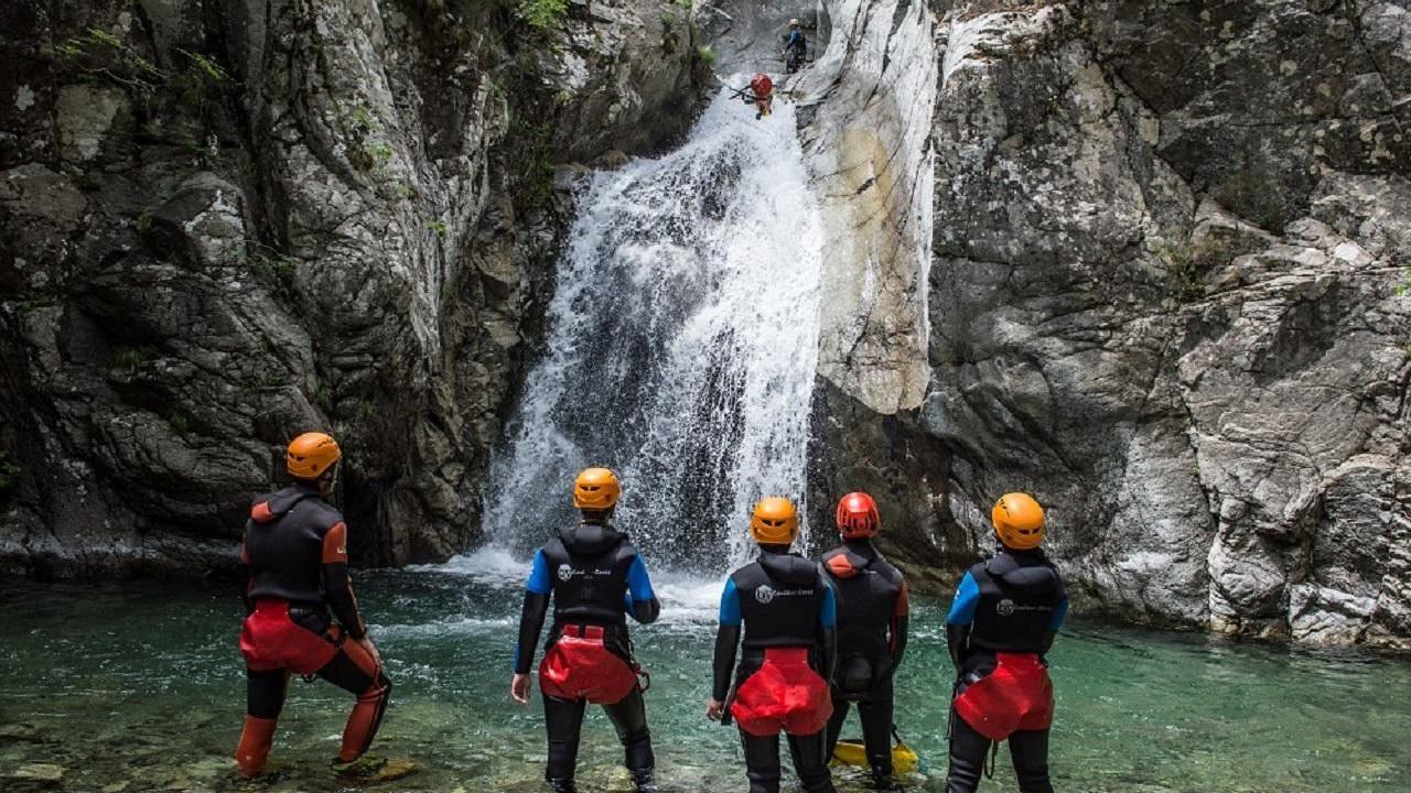 Un groupe en combinaison de canyoning observe une cascade dans les gorges corses