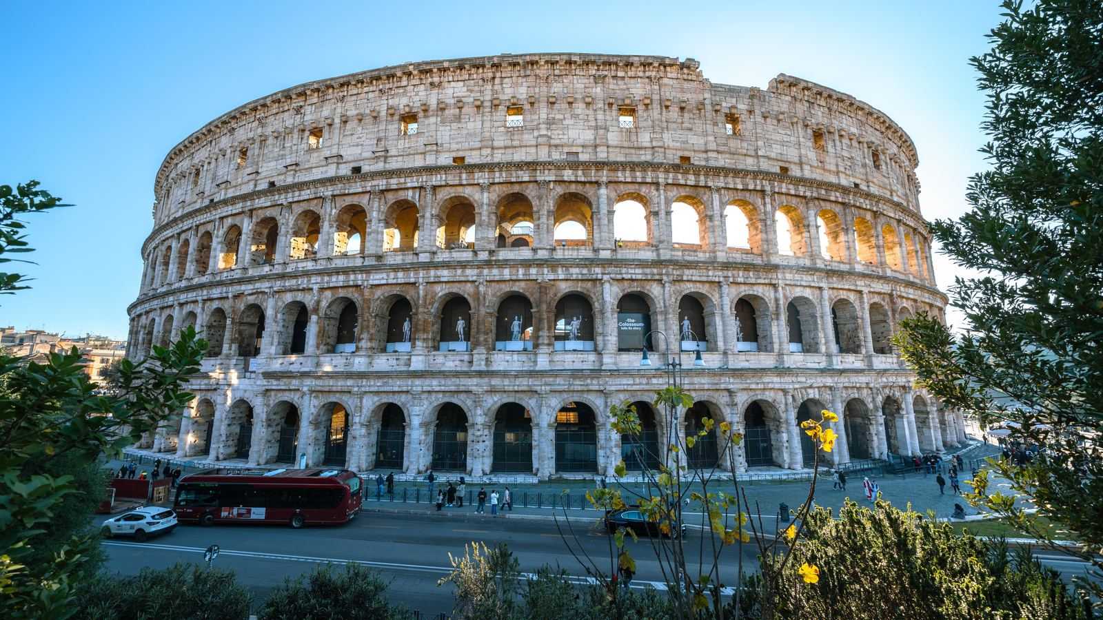 La façade extérieure du Colisée de Rome, ses quatre niveaux d'arcades sous un ciel dégagé