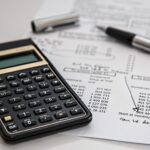 Une calculatrice posée sur un tableau de chiffres, avec un stylo
