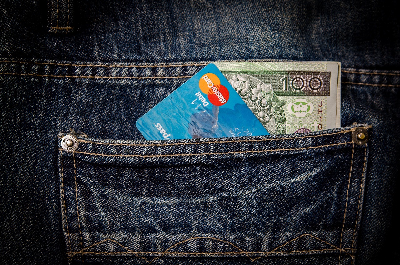 Une carte bancaire et un billet dépassent de la poche arrière d'un jean