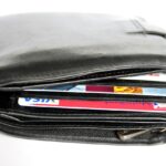 Un portefeuille en cuir noir laisse dépasser une carte Visa et une carte Mastercard