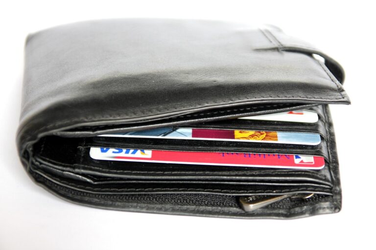 Un portefeuille en cuir noir laisse dépasser une carte Visa et une carte Mastercard